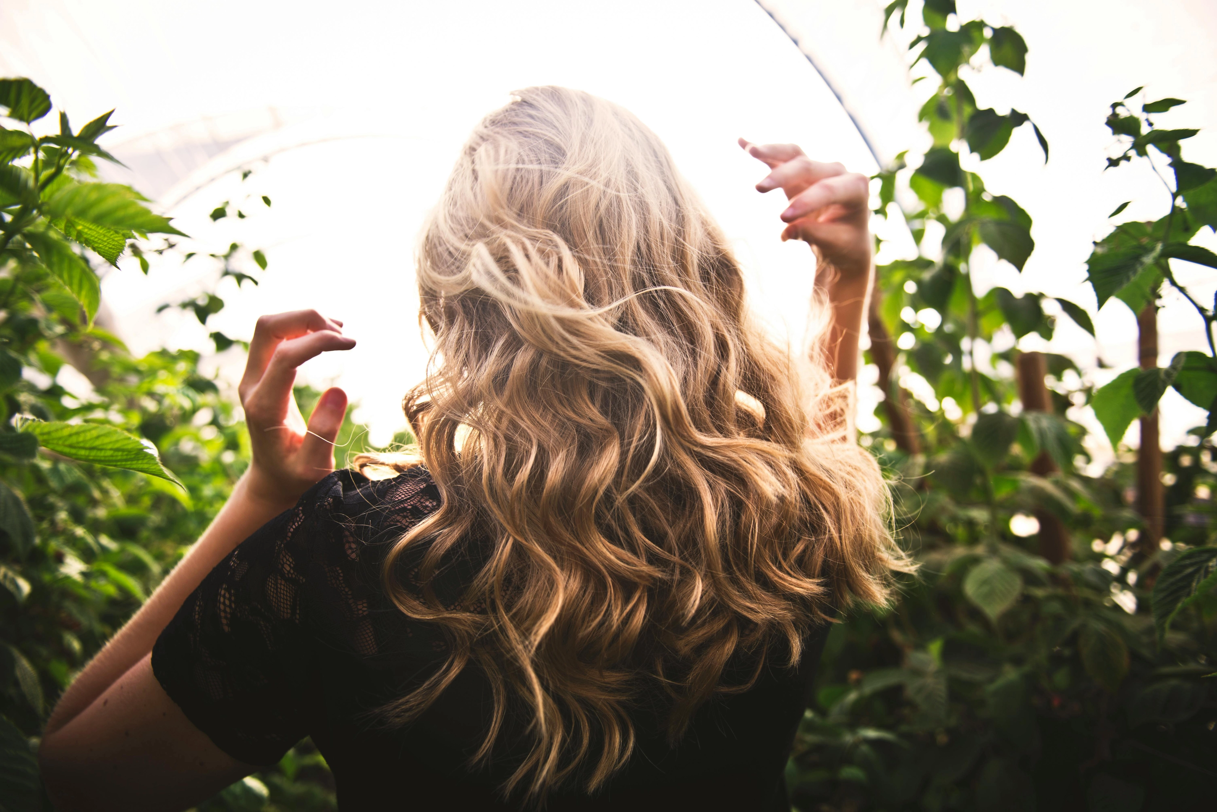 Blondhaarige Frau, Die Zwischen Grünen Pflanzen Steht