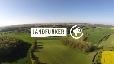 Luftbild von Feldern und kleinen Wäldern unter blauem Himmel mit dem weißen Schriftzug „LANDFUNKER“ und einem Megafon-Logo in der Bildmitte.