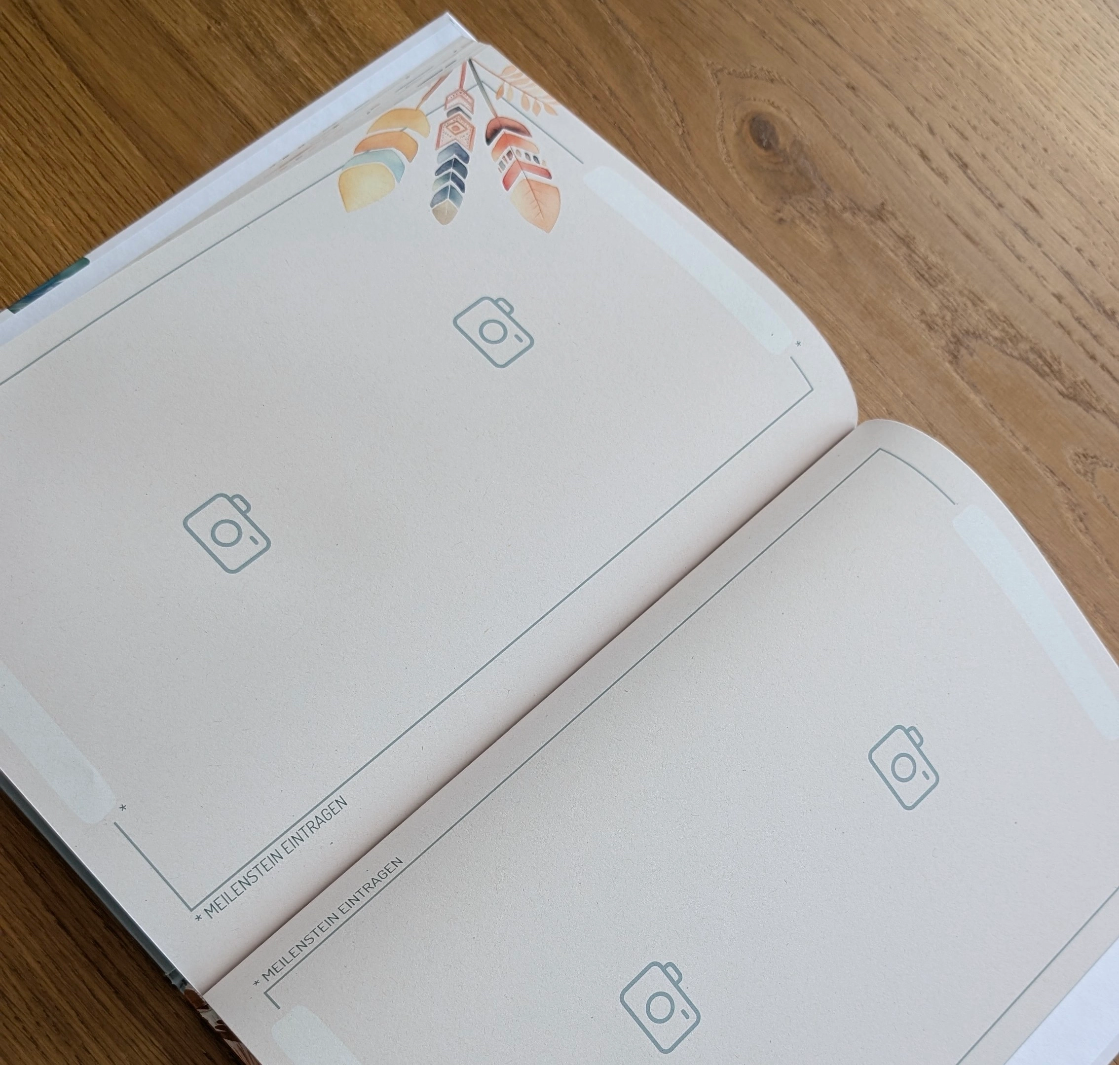 Offenes Fotoalbum/Scrapbook mit leeren Foto-Platzhaltern und Kamera-Symbolen auf einem Holztisch.