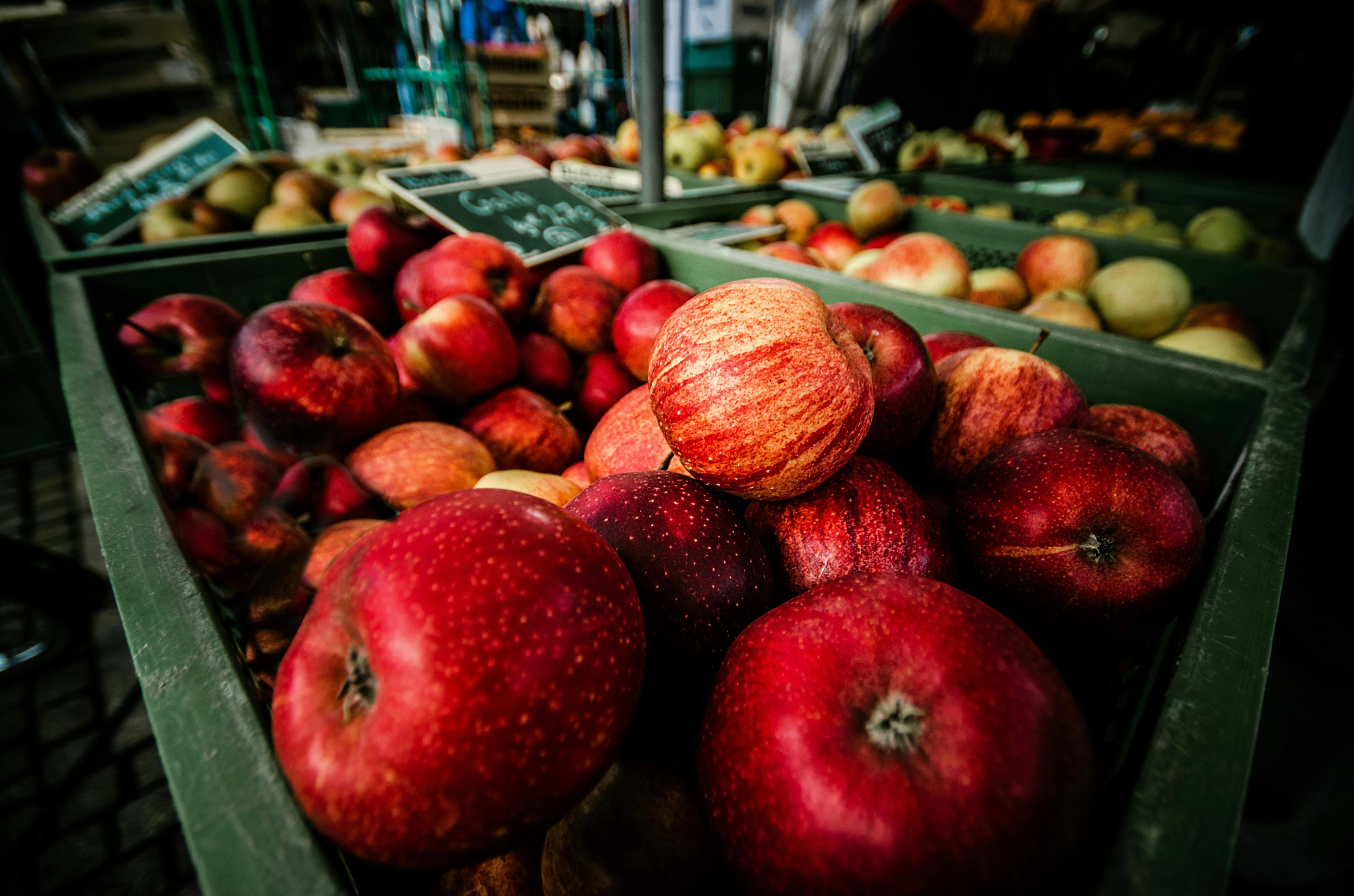 Rote und gelbliche Äpfel in Kisten auf einem Marktstand, Nahaufnahme.
