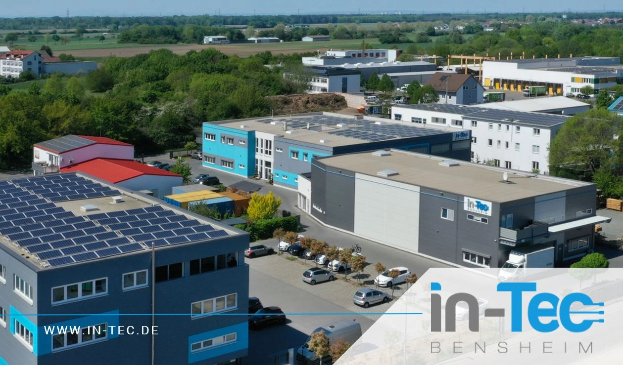 Luftbild eines Gewerbeparks mit Industriegebäuden, Parkplätzen und Solarpanelen auf den Dächern