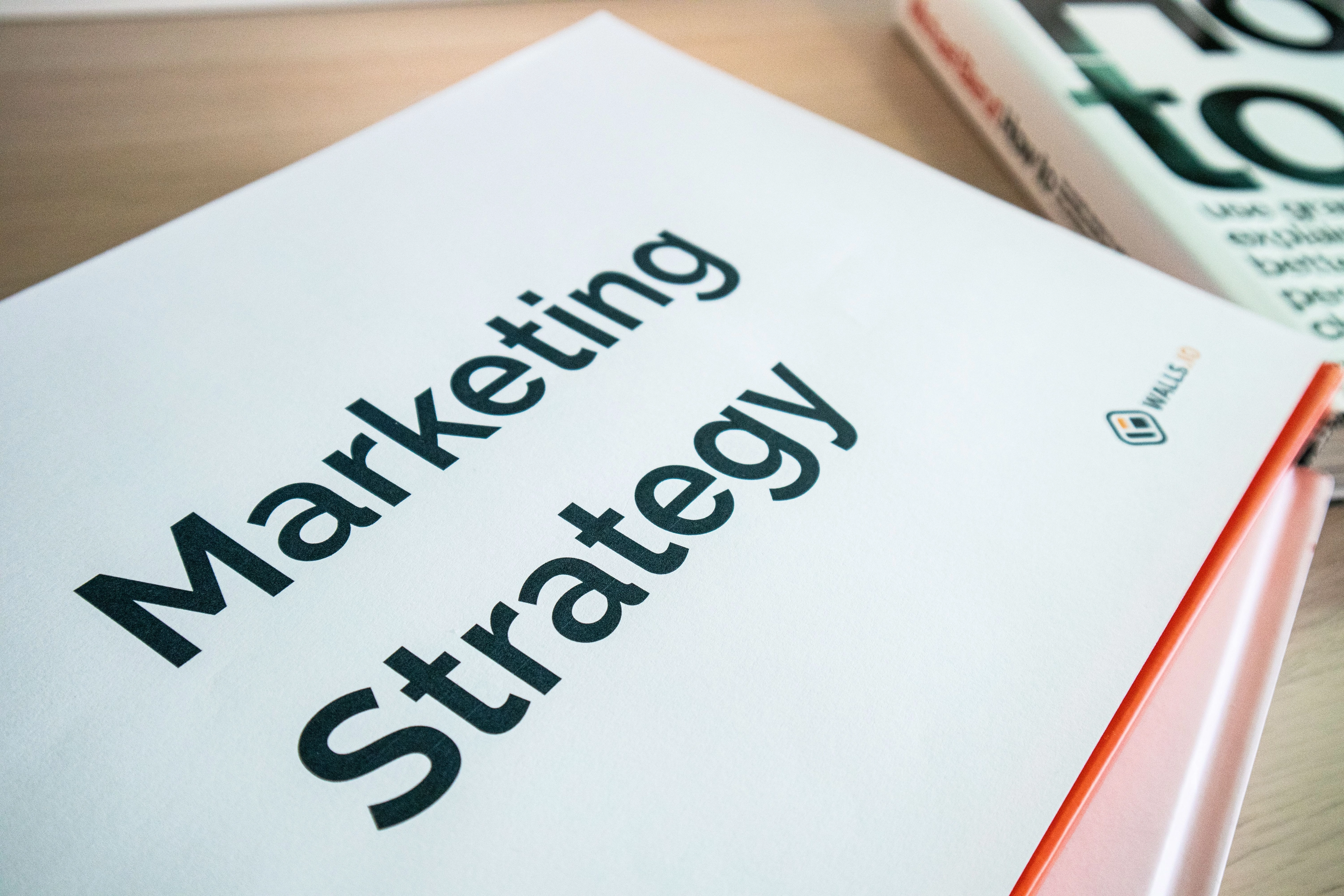 Broschüre mit der Titelaufschrift „Marketing Strategy“ liegt auf einem Schreibtisch.