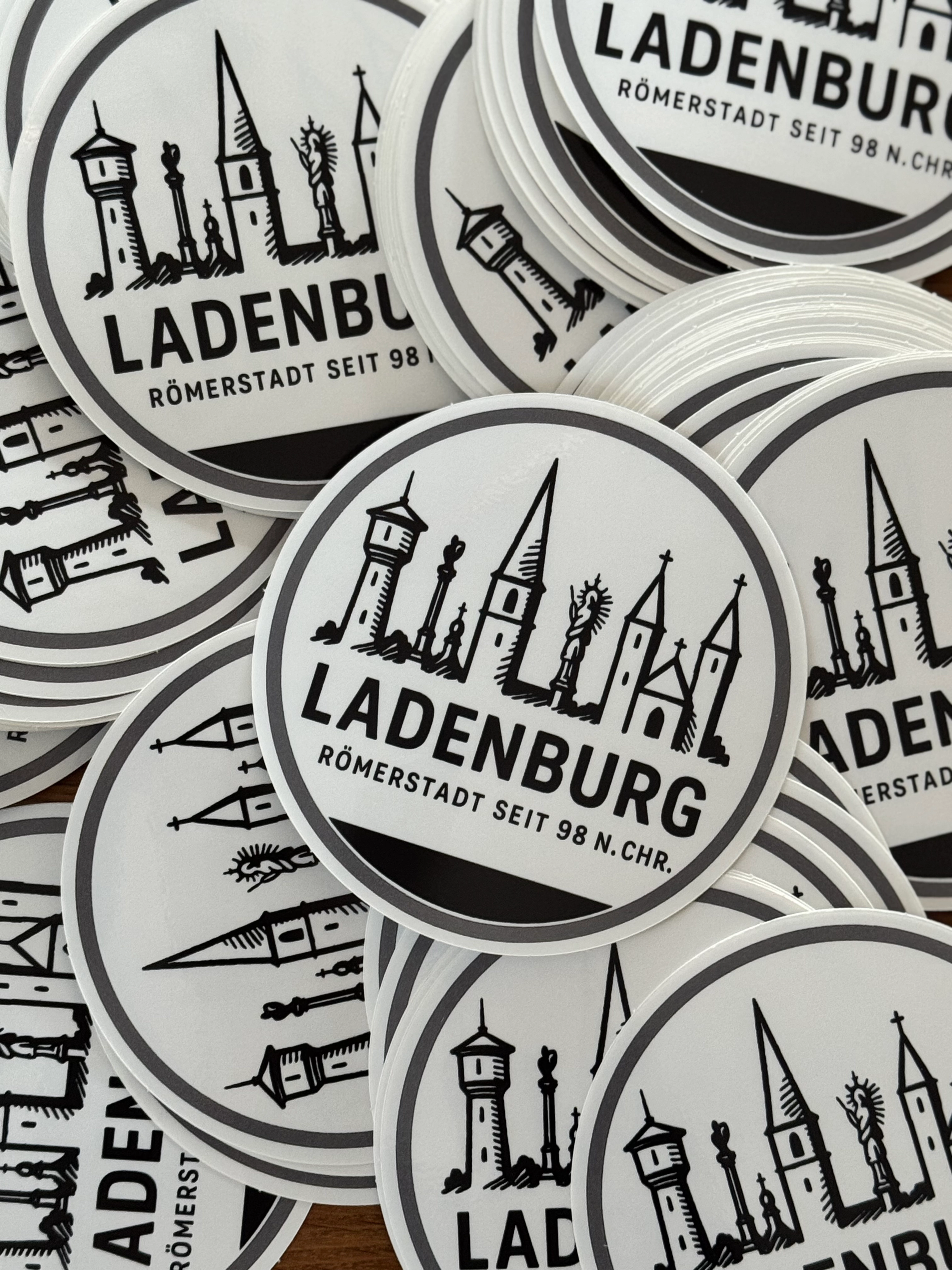 Mehrere runde Aufkleber mit schwarzer Stadt-Silhouette und der Aufschrift ‚LADENBURG – Römerstadt seit 98 n. Chr.‘