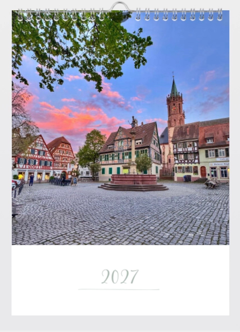 Kalenderblatt 2027 mit Foto eines historischen Marktplatzes, Brunnen, Fachwerkhäusern und einem Kirchturm bei Sonnenuntergang.