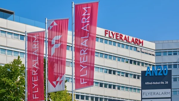 Bürogebäude mit roten FLYERALARM-Fahnen, Firmenbeschriftung und Straßenschild.