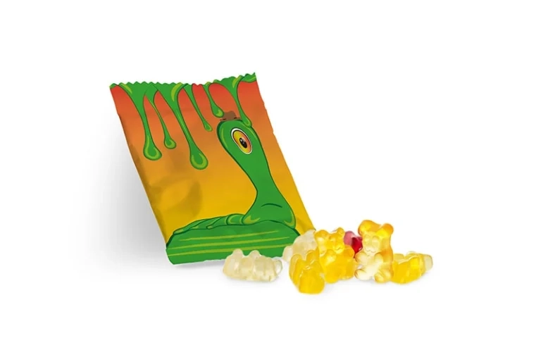 Geöffnete Süßigkeitentüte mit gelben und weißen Gummibärchen und grünem Cartoon auf der Verpackung.